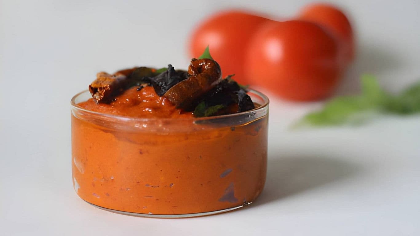 Glass bowl of spicy tomato chutney with garnish
