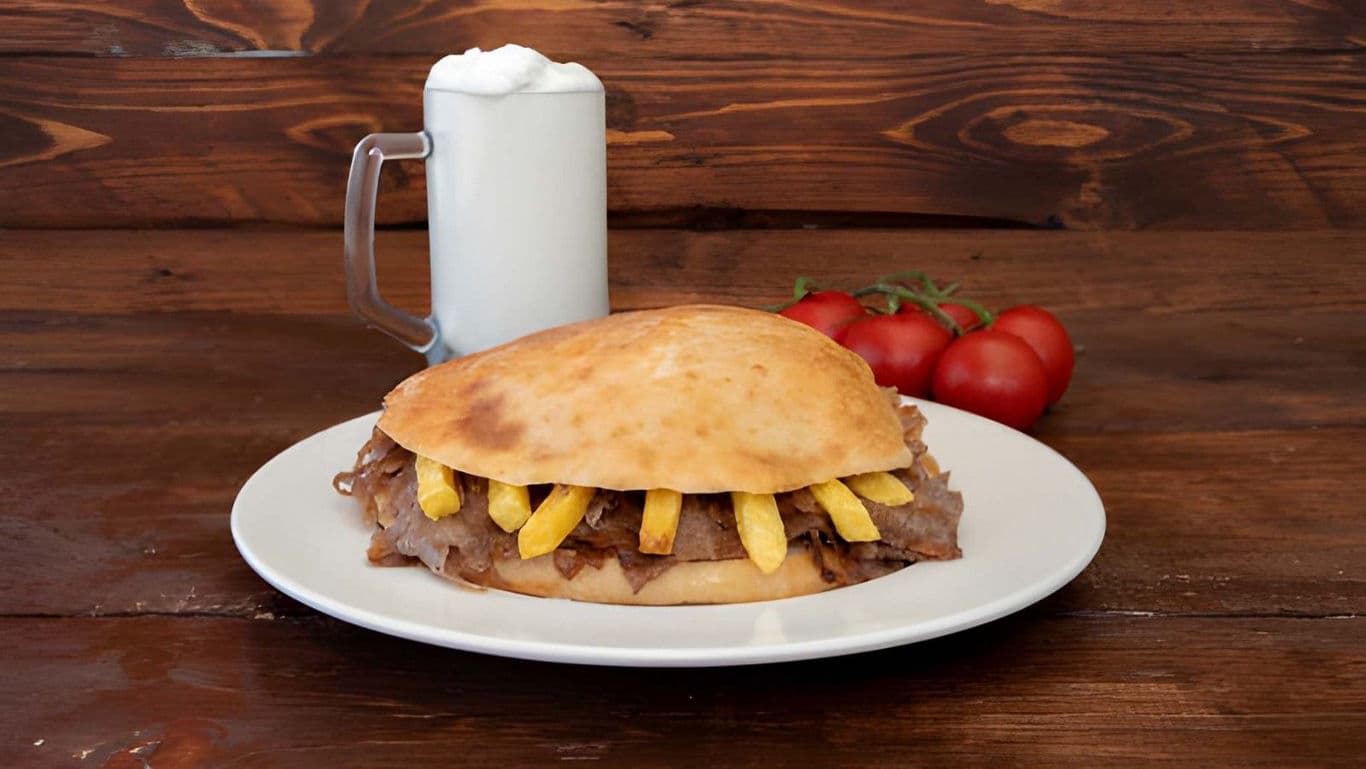 Gyro sandwich with fries and frothy drink on plate