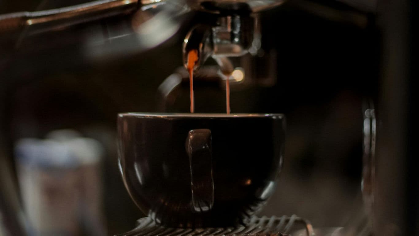 Espresso machine brewing coffee into cup