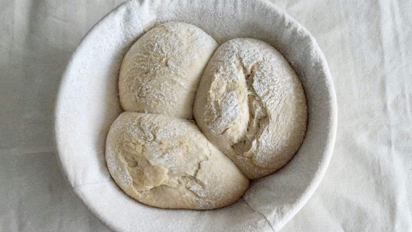 Three rustic bread loaves in proofing basket