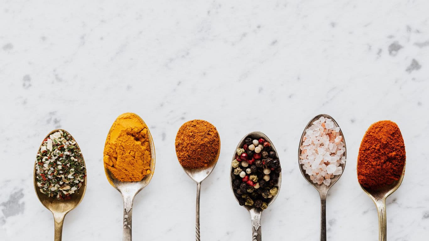 Assorted colorful spices in metal spoons