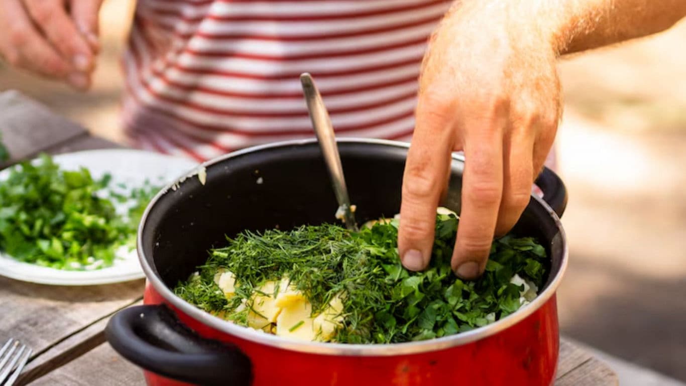 Cooking with fresh herbs in red pot