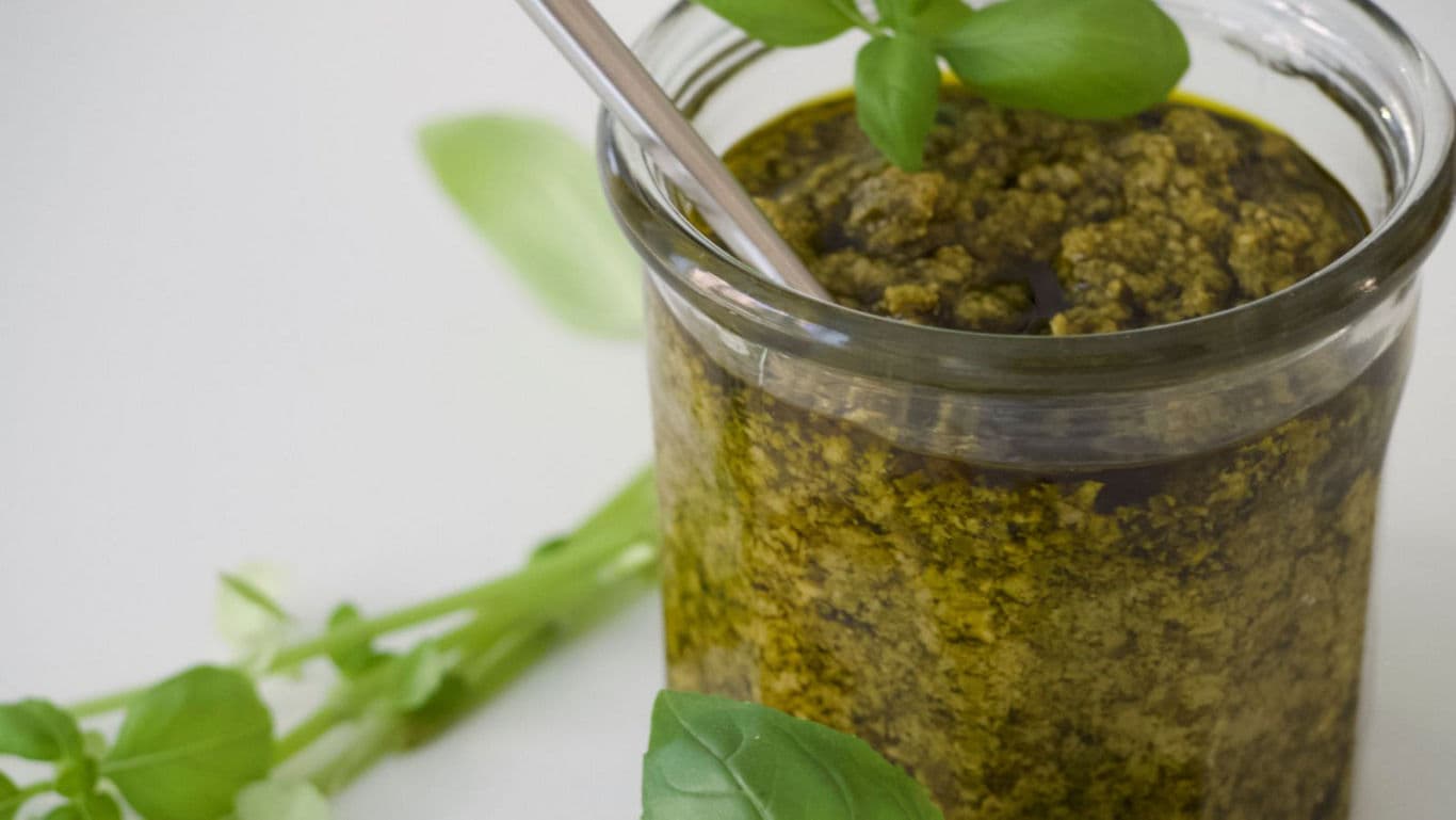 Glass jar of fresh basil pesto sauce
