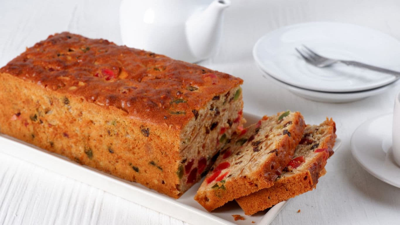Sliced fruitcake loaf on white platter