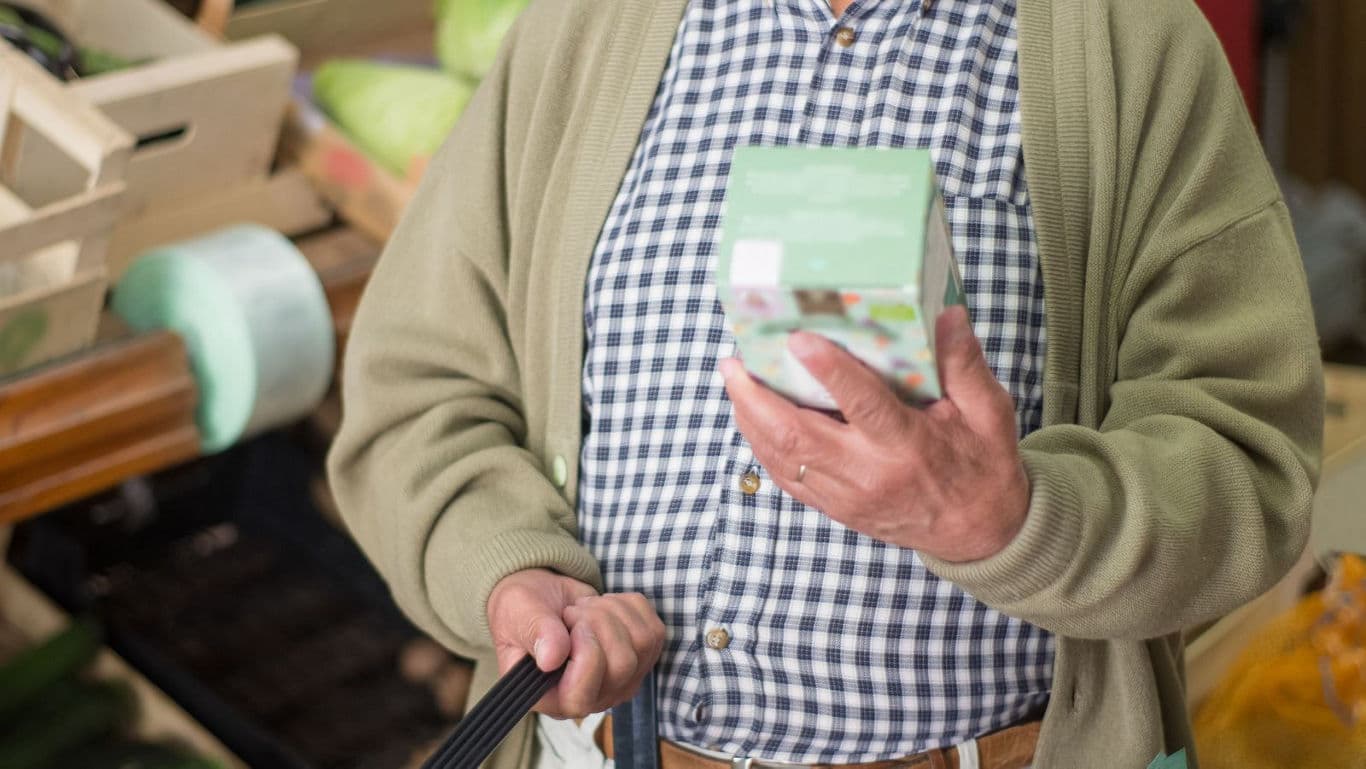 Senior shopper examining product box in store