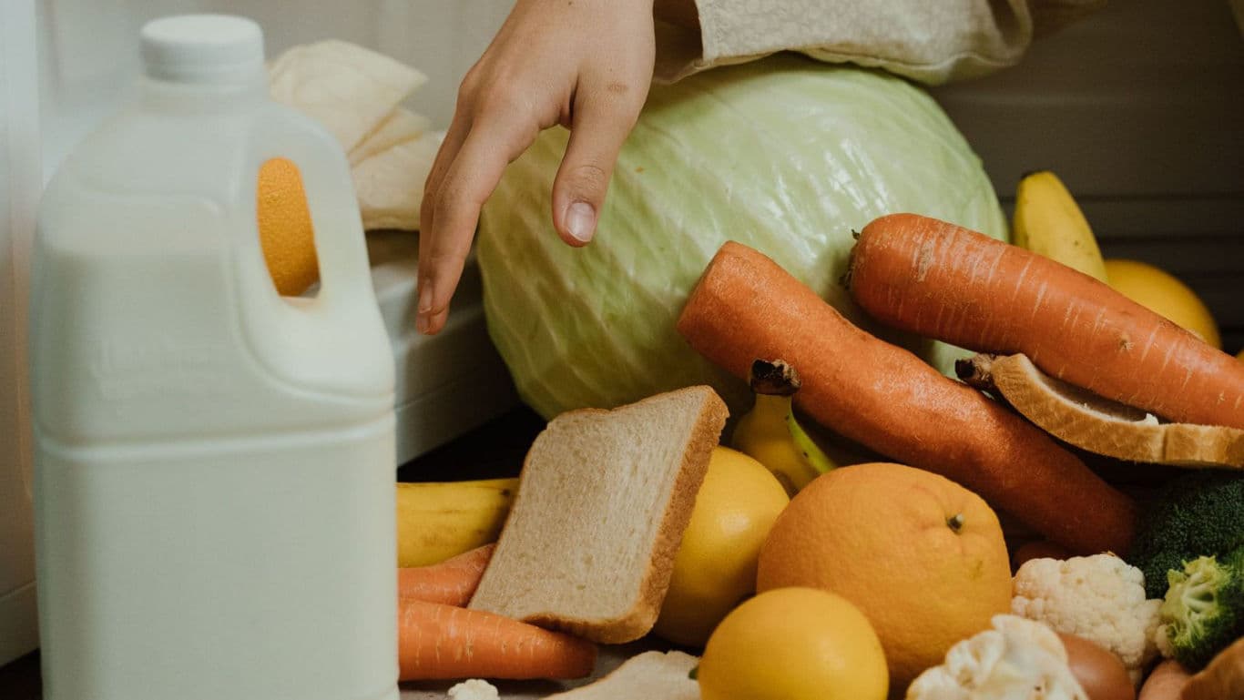 Hand Reaching Over Fresh Groceries on Table