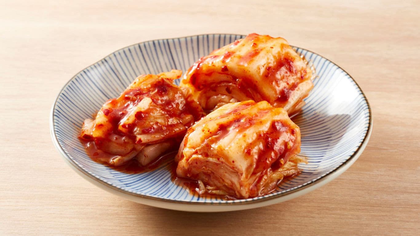Three servings of kimchi on ceramic plate