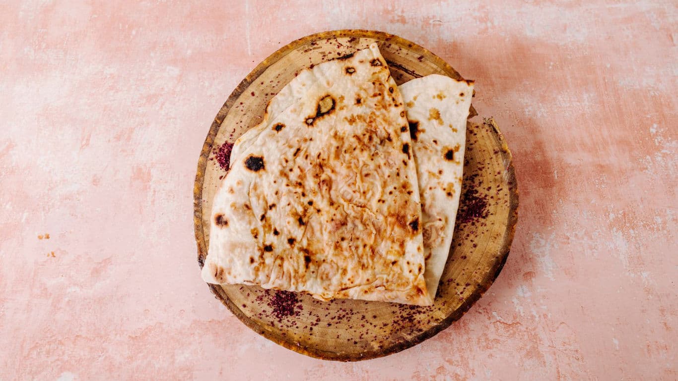 Grilled flatbread on rustic wooden plate