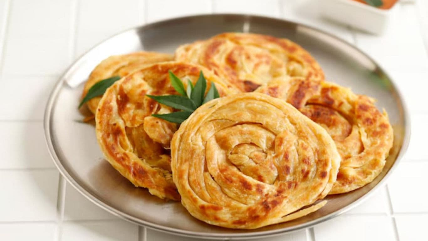 Crispy layered paratha flatbreads on metal plate