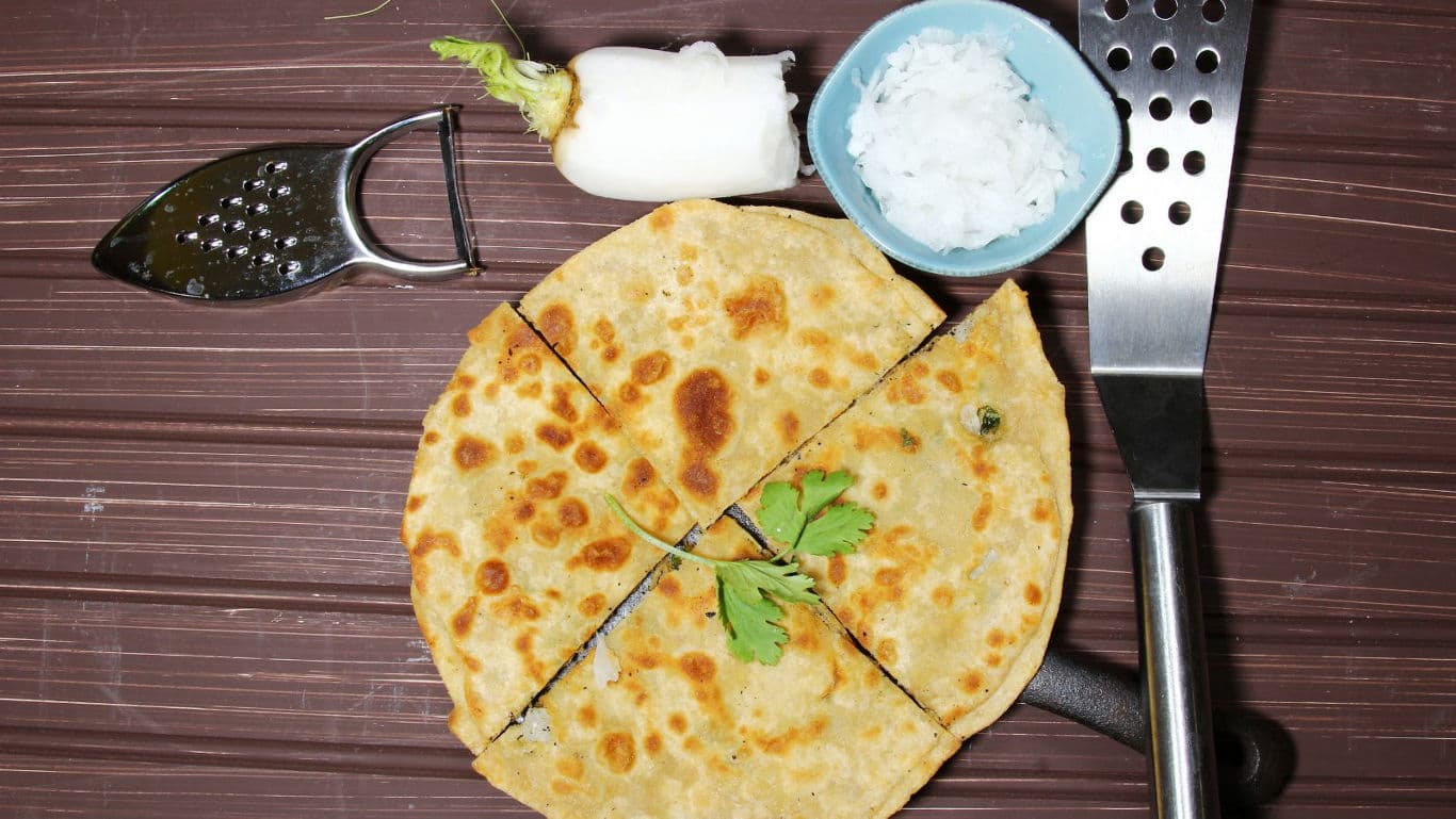 Sliced stuffed paratha with radish and kitchen tools