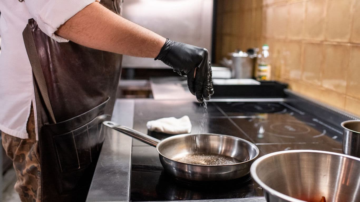 Chef Seasoning Food in Stainless Steel Pan