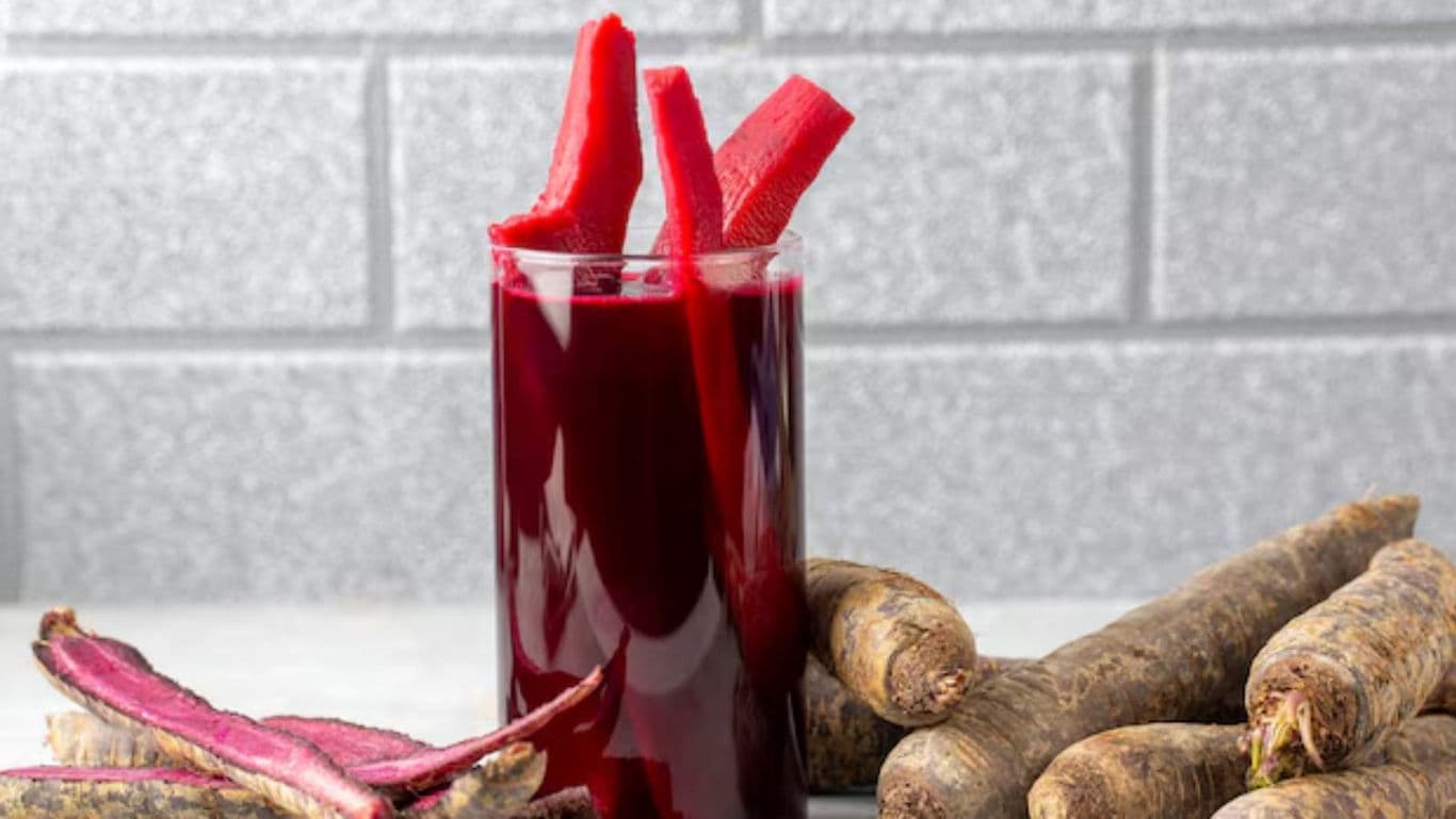 Glass of purple root vegetable juice with slices
