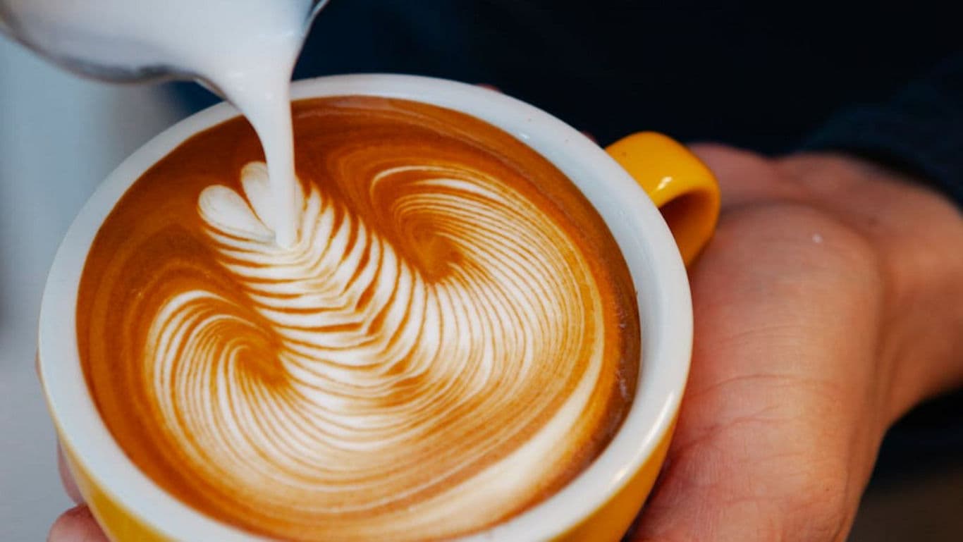 Barista pouring latte art into cappuccino