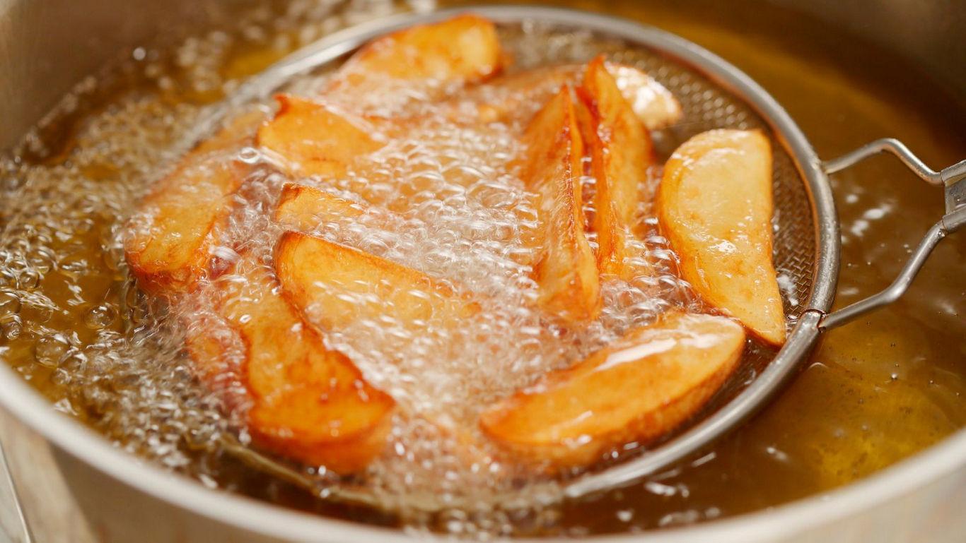 Golden potato wedges frying in hot oil