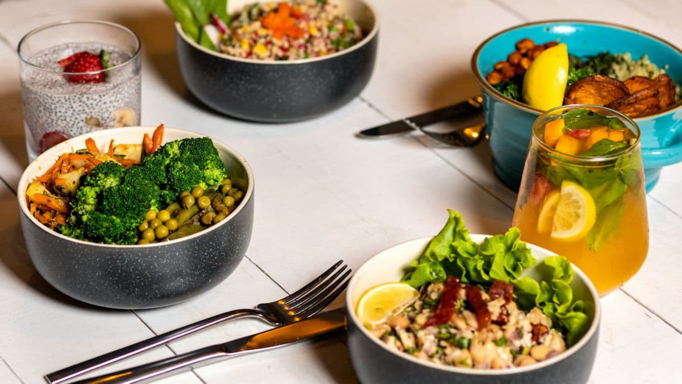 Colorful healthy meal bowls with fresh vegetables and drinks