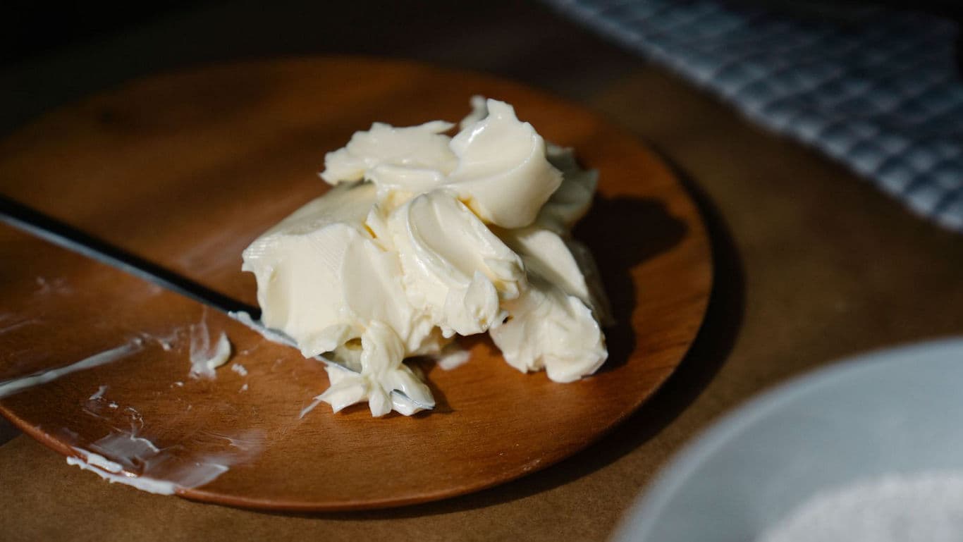 Soft butter on wooden plate in kitchen