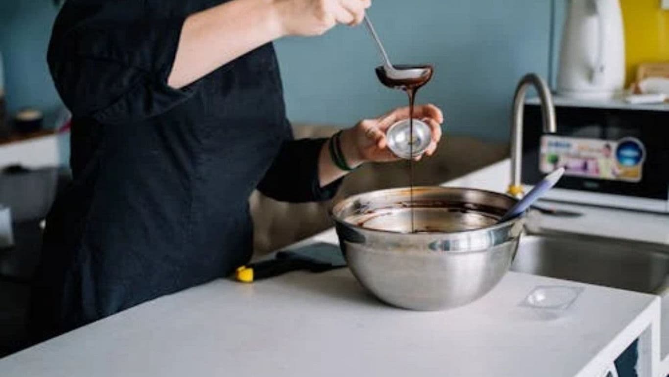 Person pouring chocolate sauce into mixing bowl
