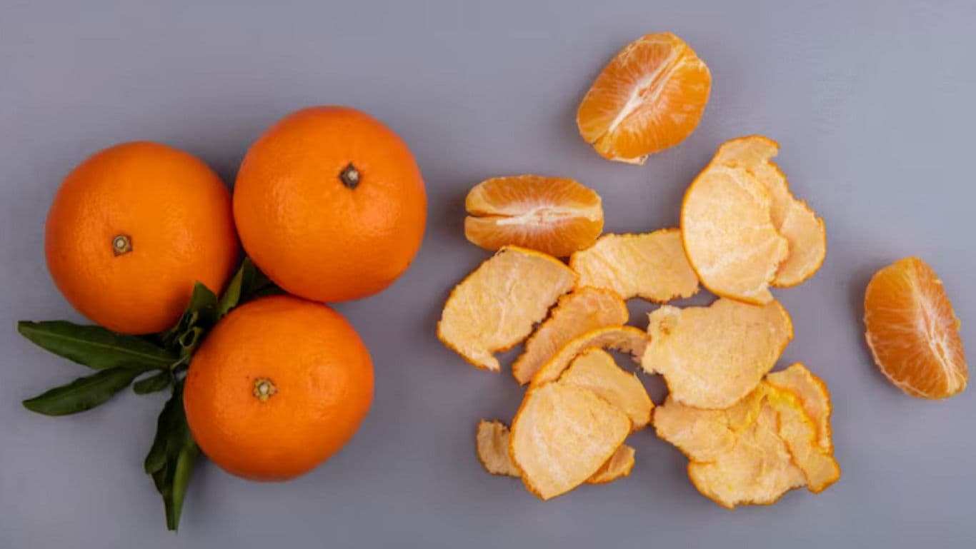 Whole and peeled oranges on gray background