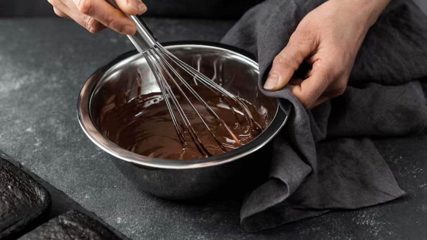 Person whisking chocolate batter in metal bowl