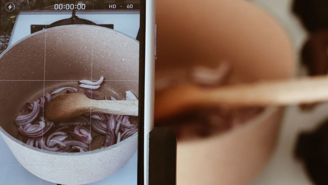 Smartphone filming onions cooking in pot