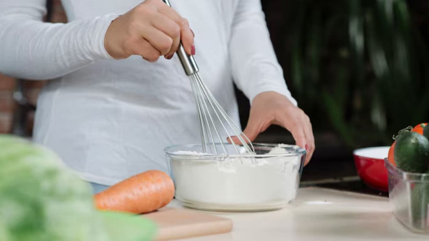 Person Whisking Batter in Kitchen Setting