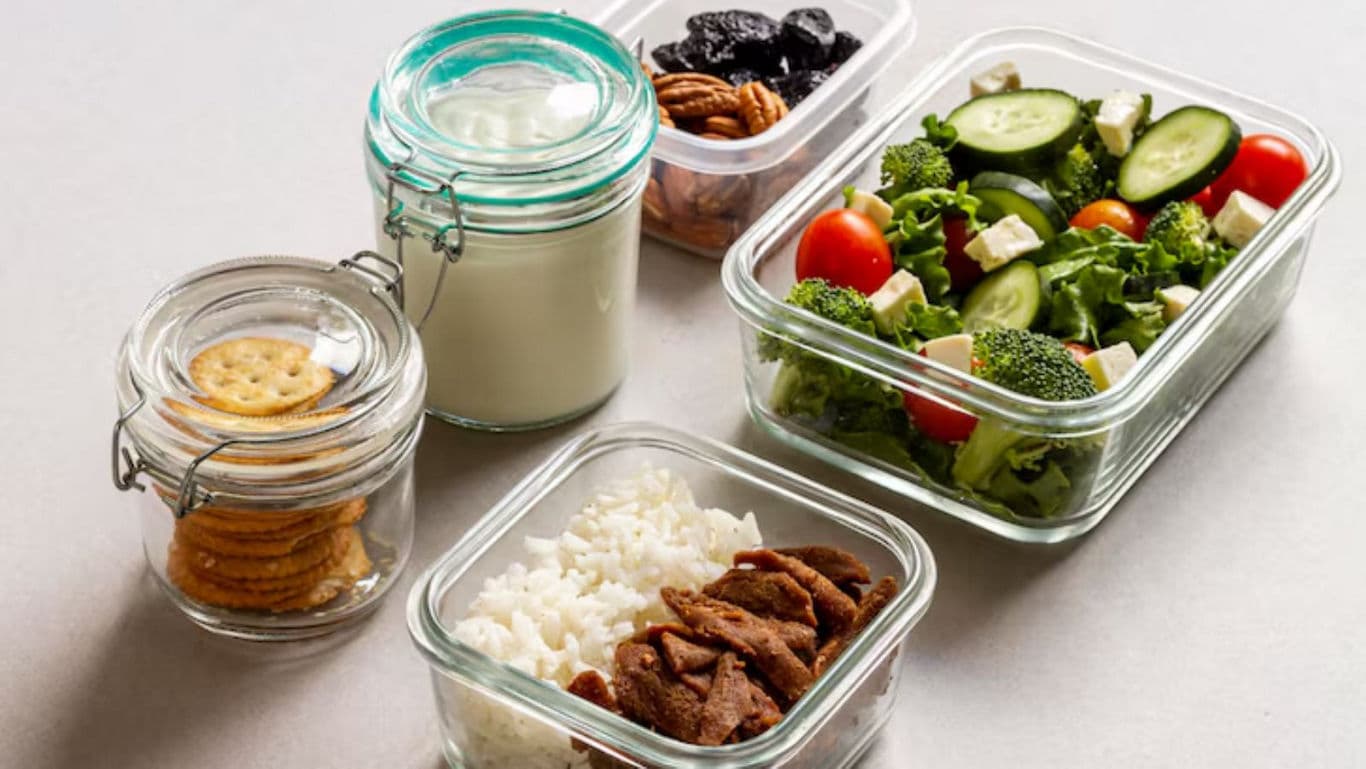Healthy meal prep with salad, rice, and snacks in glass containers