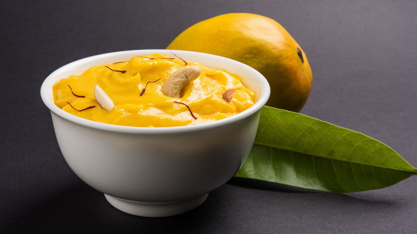 Mango dessert in white bowl with nuts and saffron
