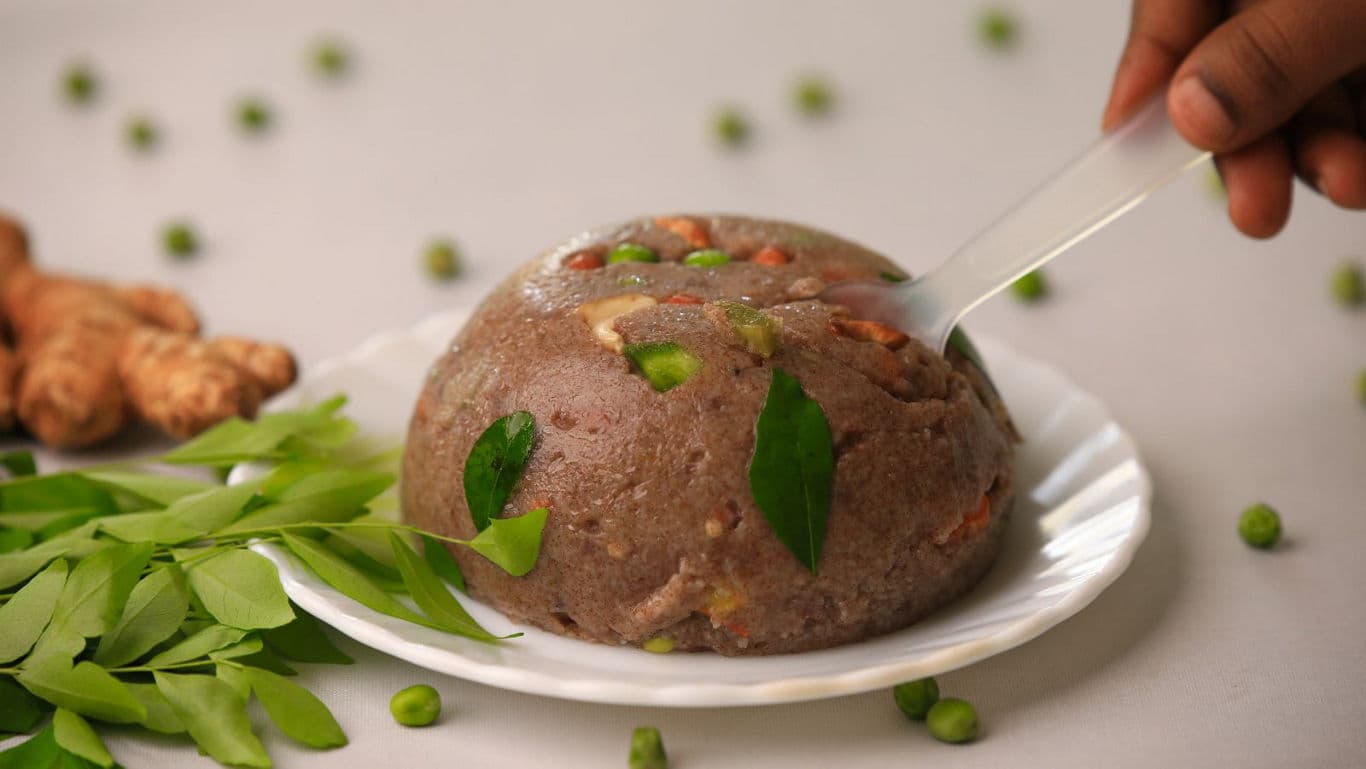 Hand Serving Traditional Indian Ragi Upma on Plate
