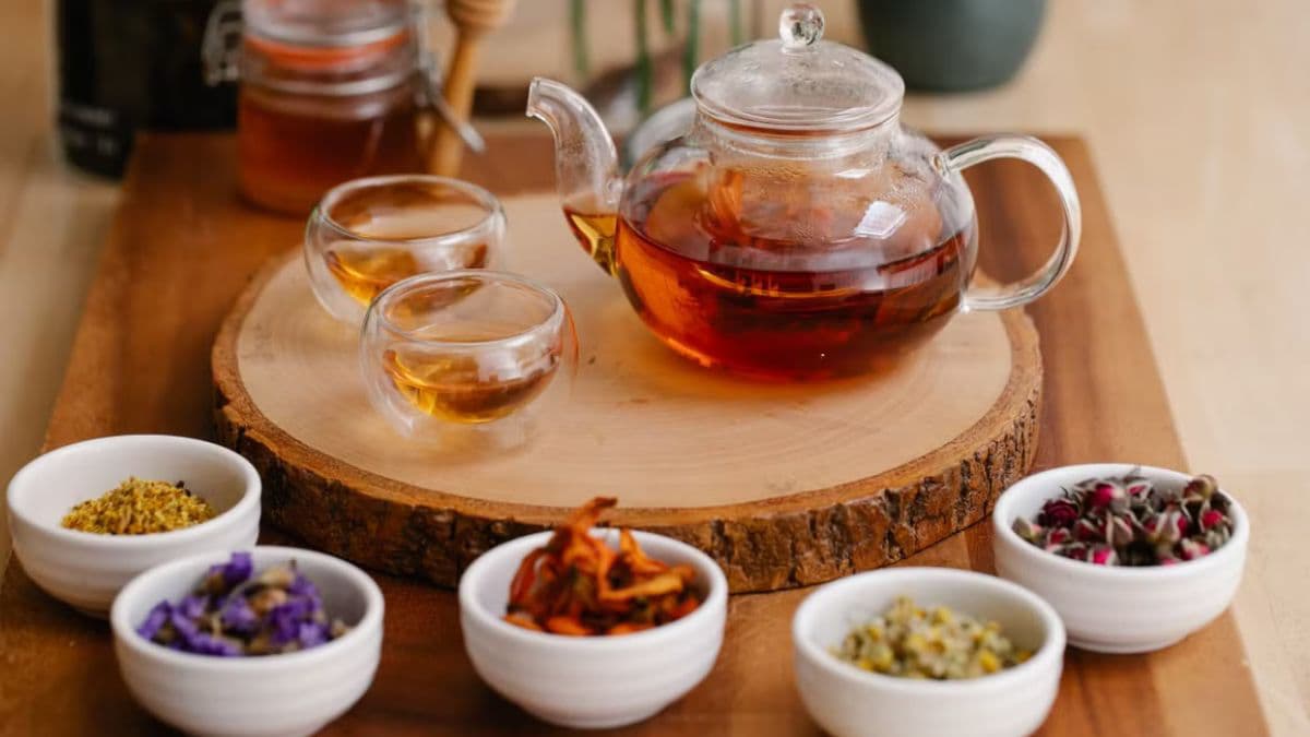 Herbal tea pot surrounded by dried herbs