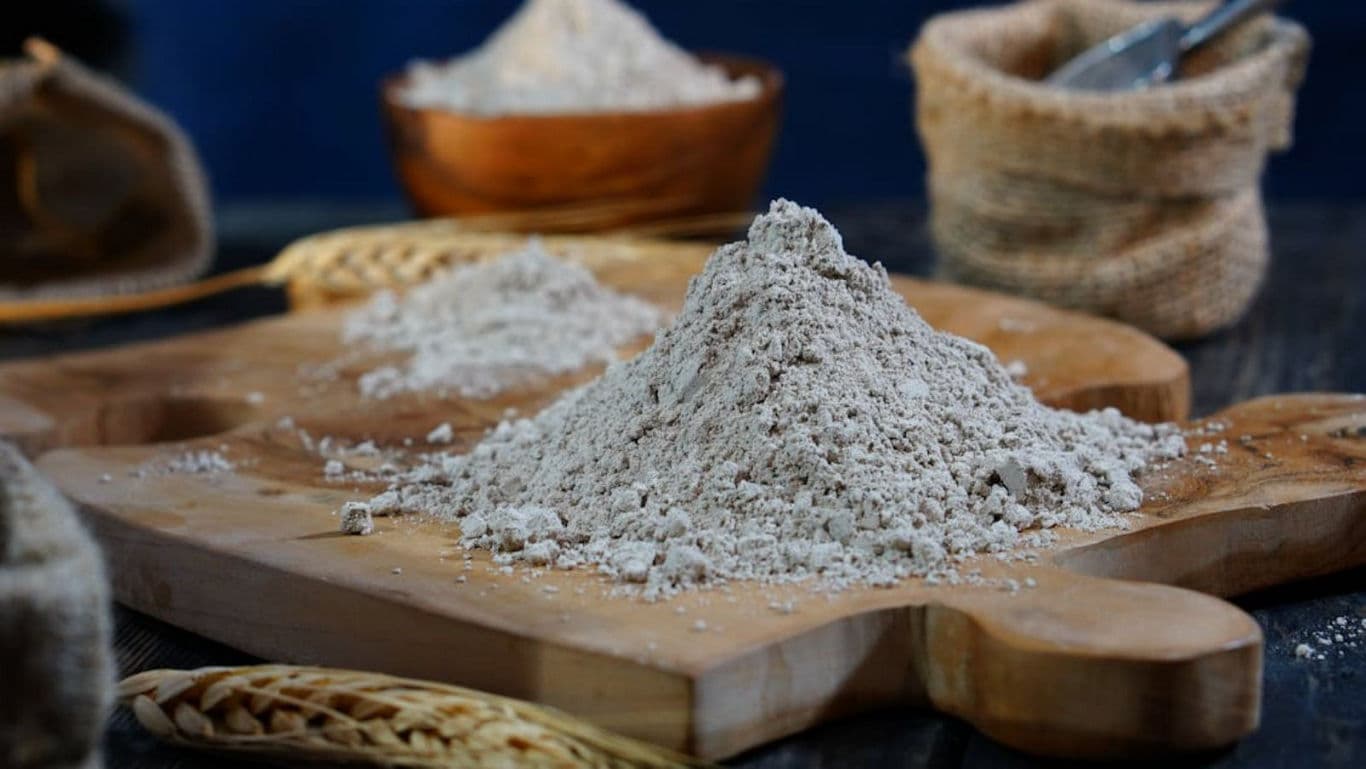Heap of whole grain flour on wooden board