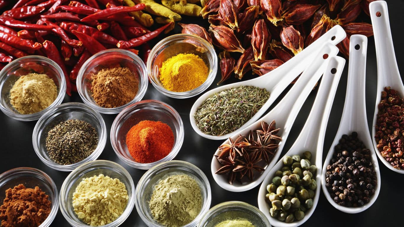 Assorted colorful spices in bowls and spoons