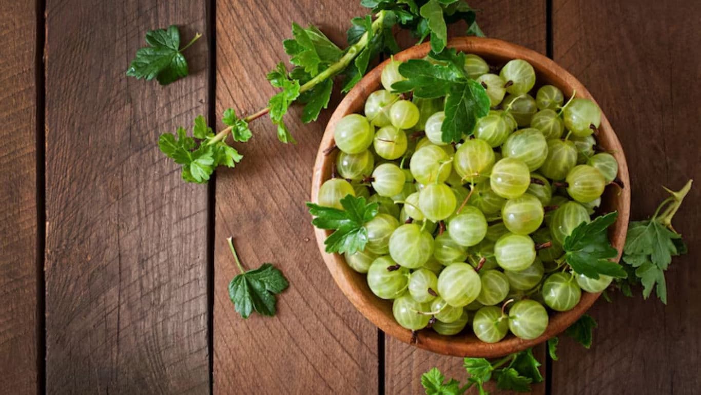 Fresh green gooseberries in wooden bowl