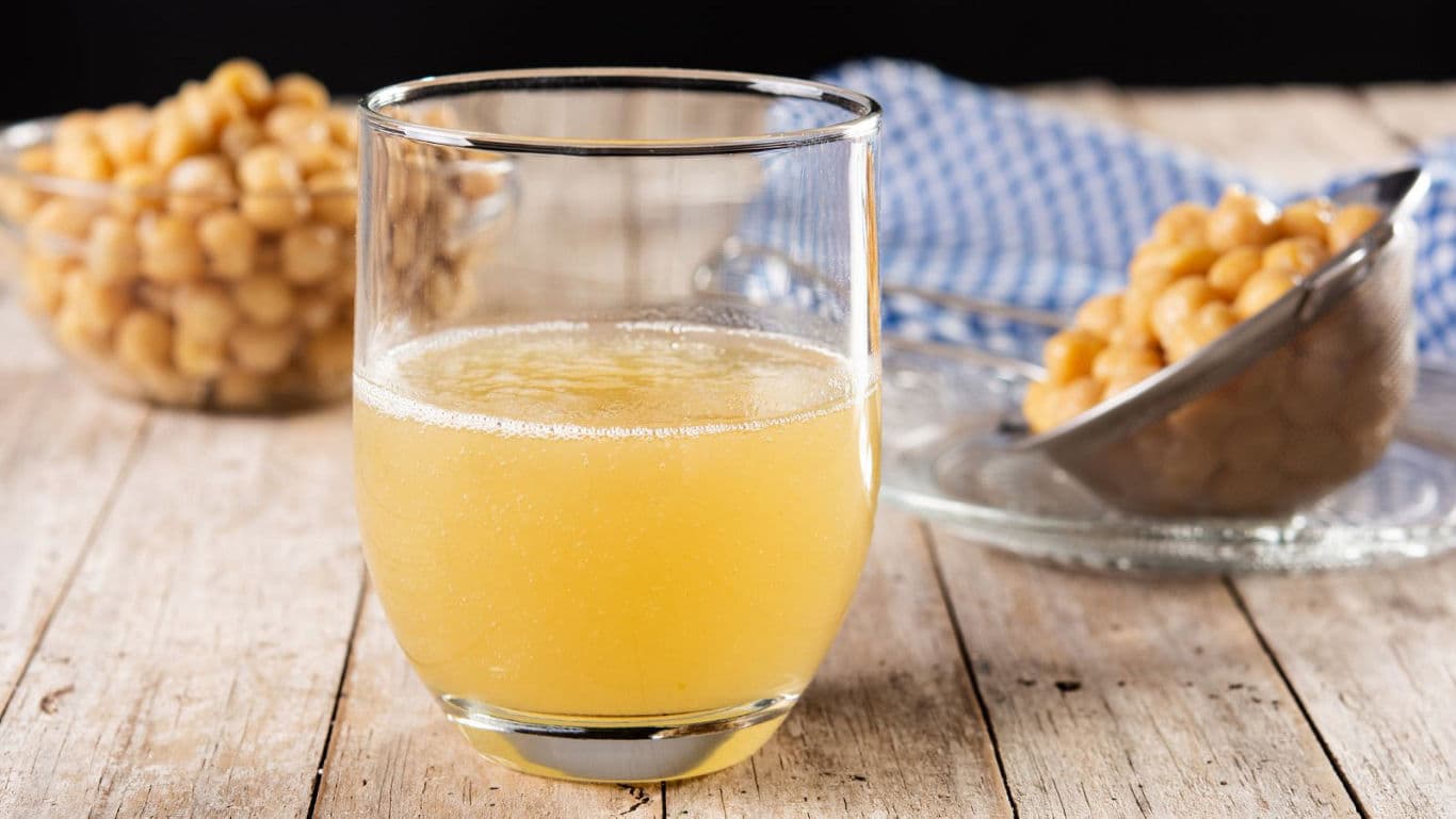 Glass of chickpea liquid on rustic wooden table