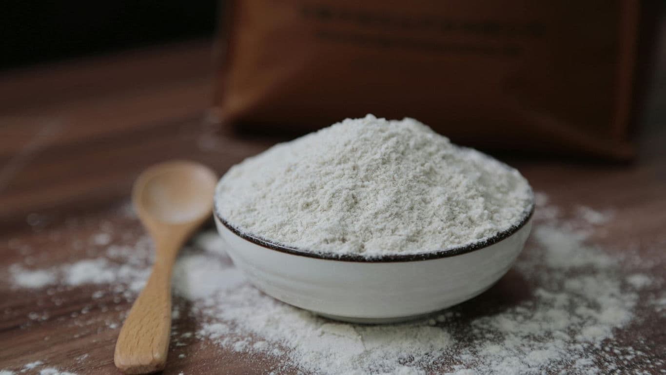 Bowl of white flour on wooden table