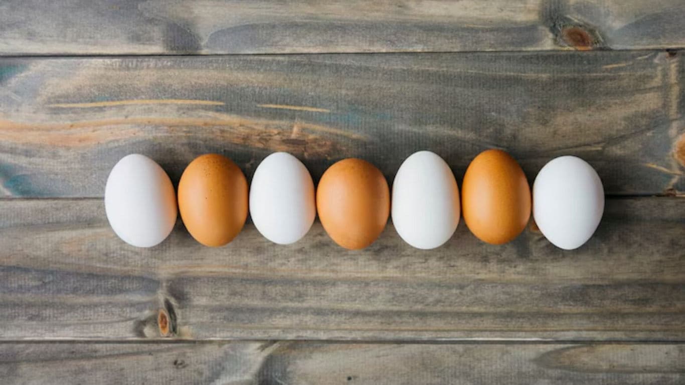 Brown and white eggs arranged on rustic wood