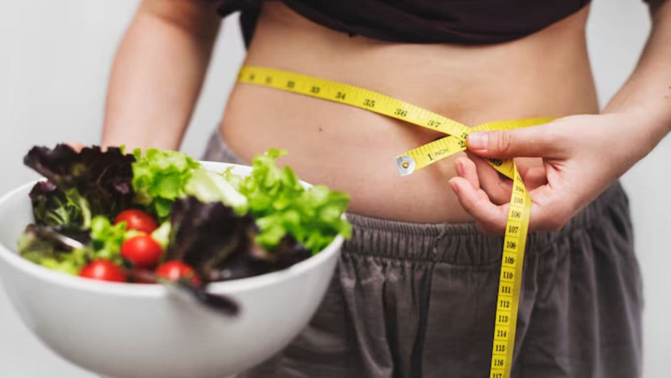Person Measuring Waist with Salad Bowl in Hand