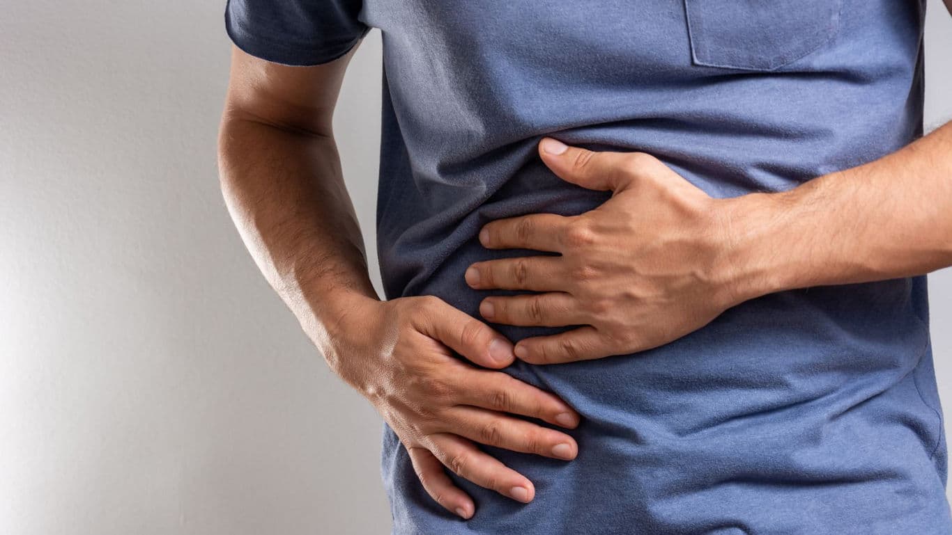 Person Holding Stomach in Discomfort Indoors