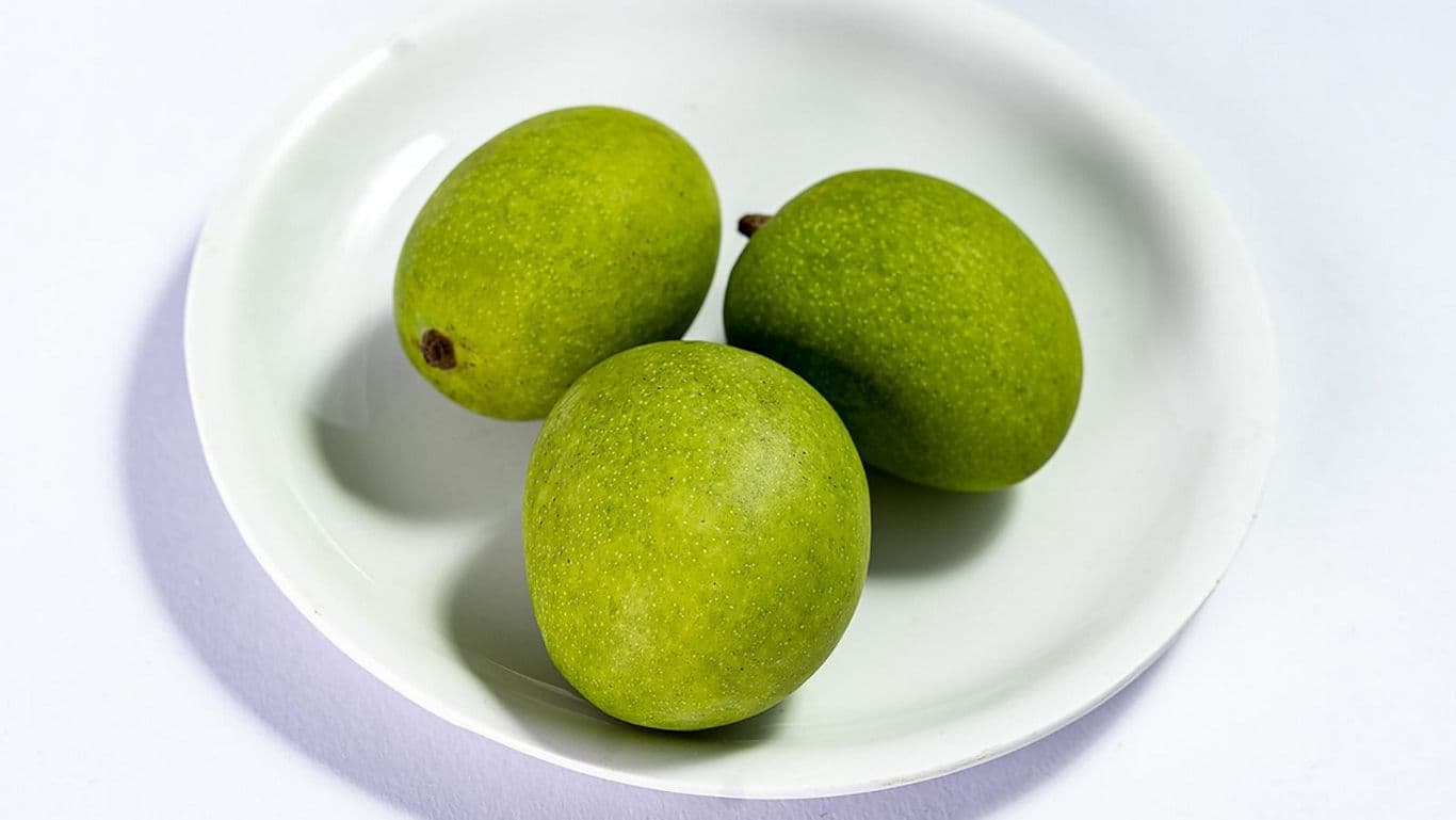 Three fresh green mangoes on plate