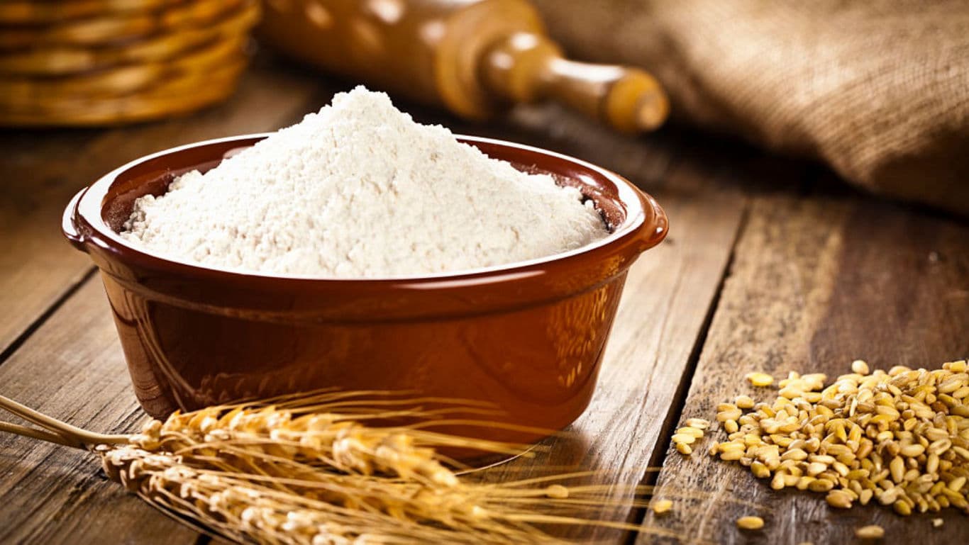 Bowl of Wheat Flour with Grains on Wooden Table