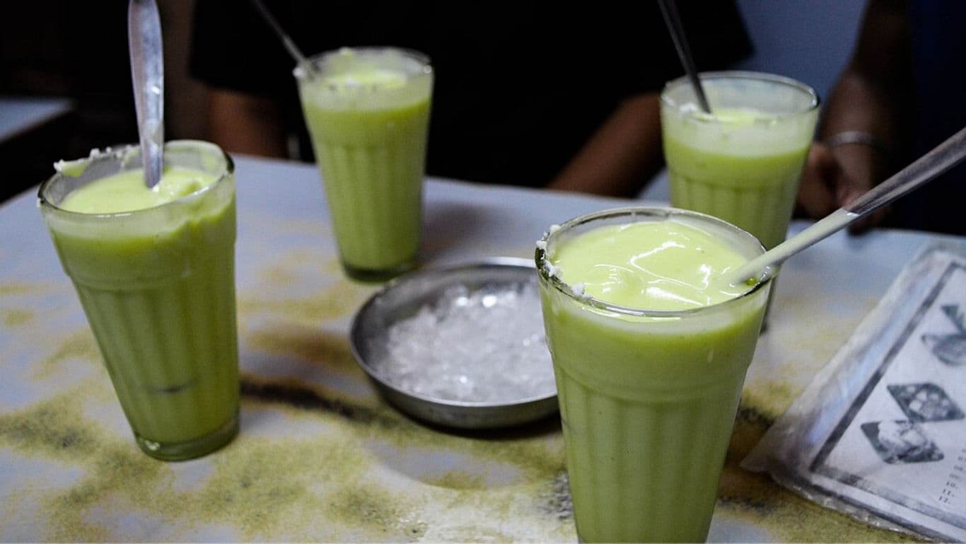 Glasses of chilled green milkshake on table