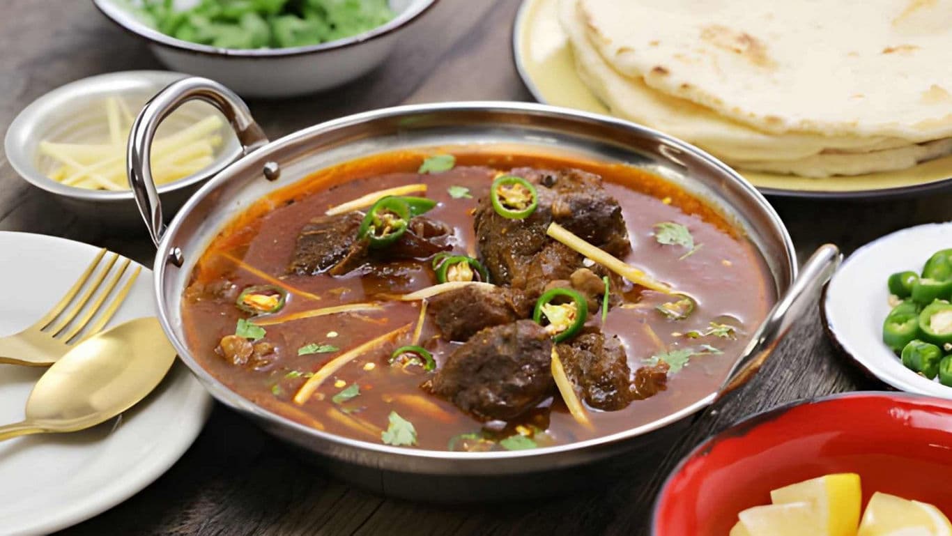 Spicy beef curry served with flatbread and garnishes