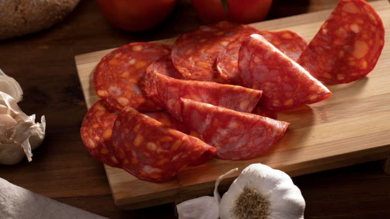 Sliced spicy salami on wooden cutting board