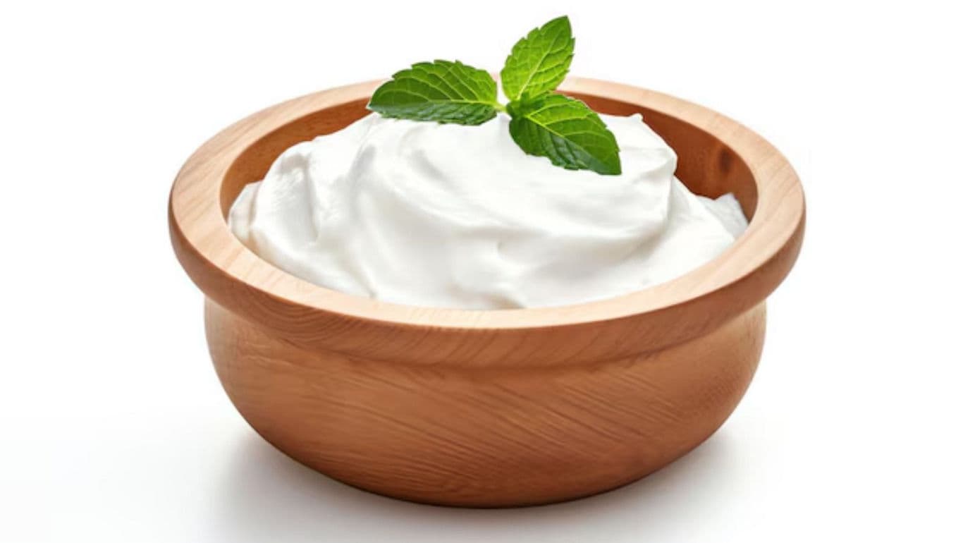 Creamy yogurt in wooden bowl with mint garnish
