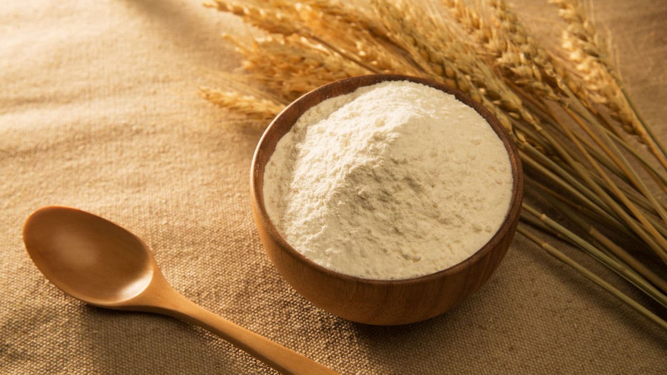 Wooden bowl of flour with wheat stalks