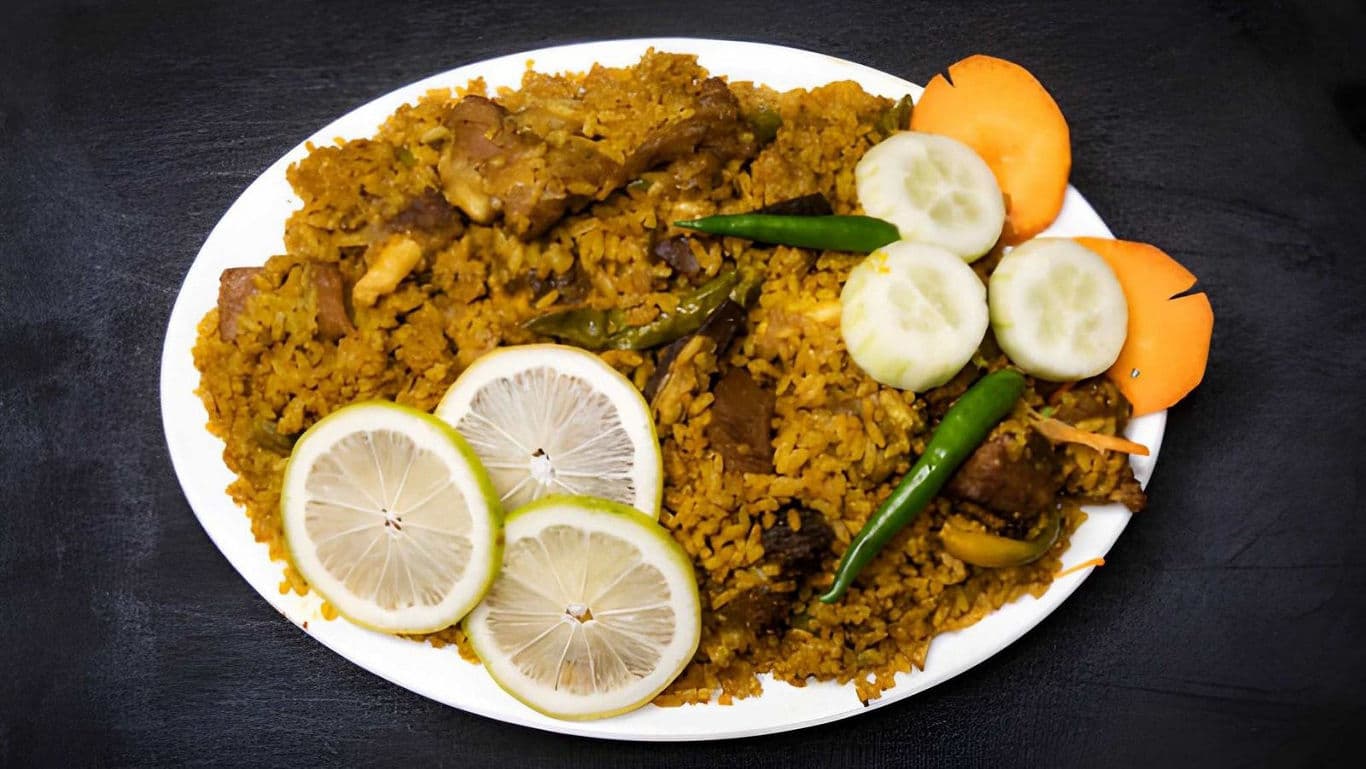 Spiced rice with meat garnished with lemon and vegetables