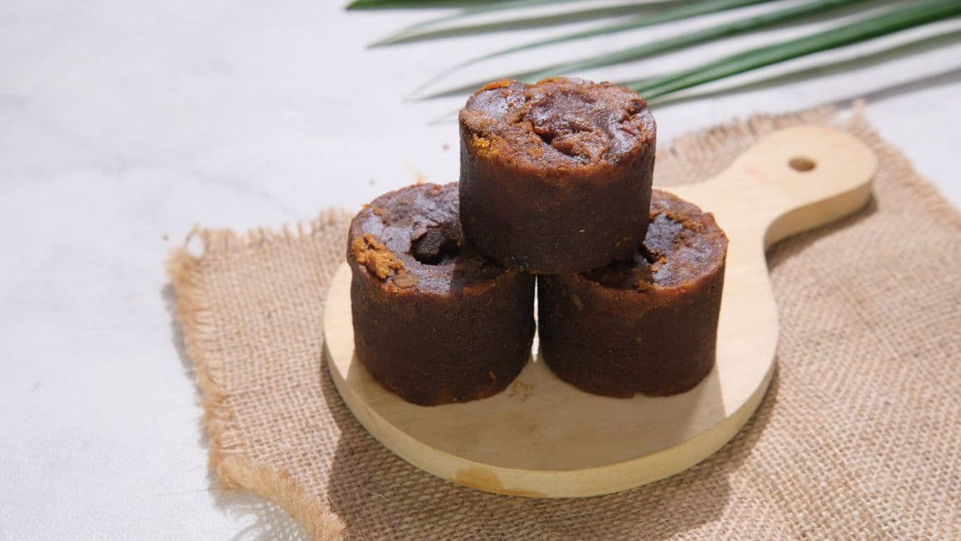 Three Cylindrical Brown Sugar Blocks on Wooden Board