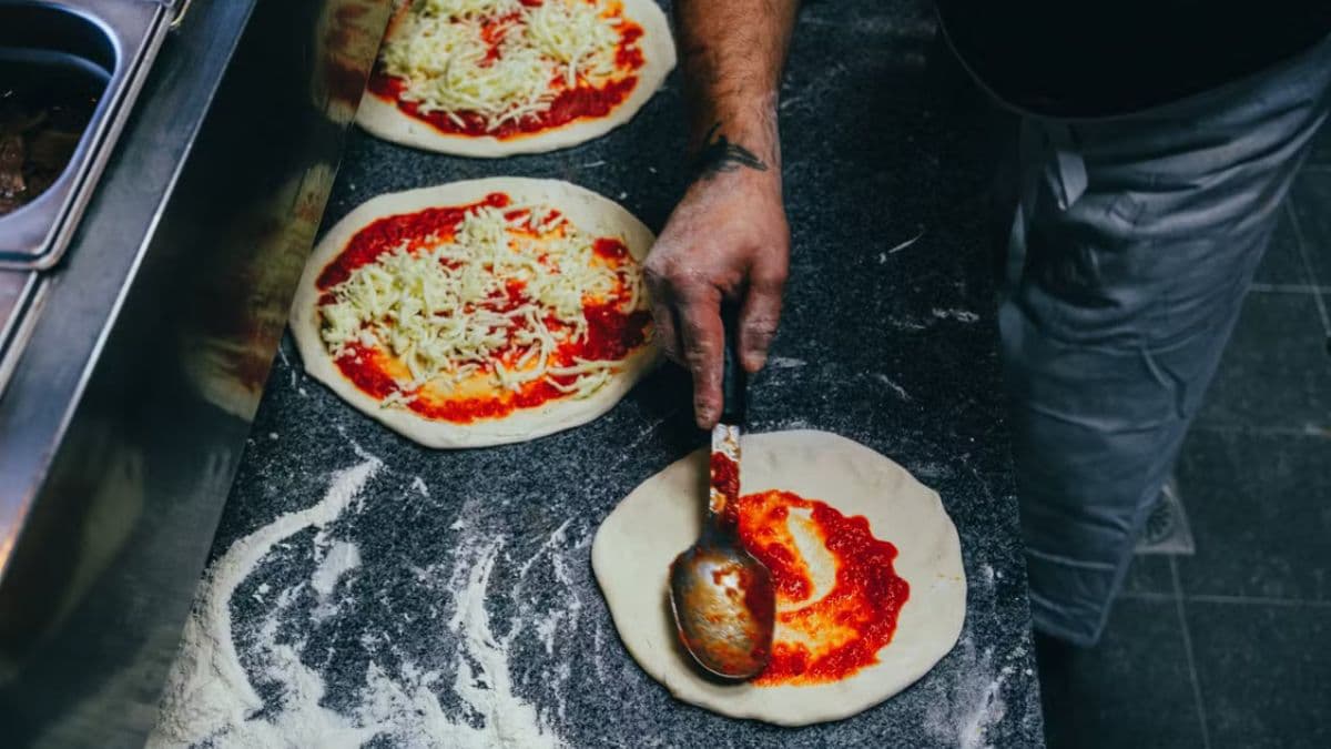 Spreading sauce on pizza base