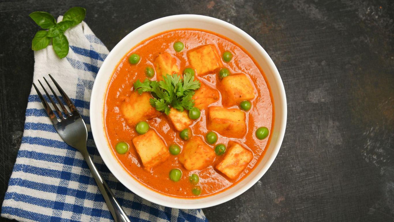 Paneer curry with peas in white bowl